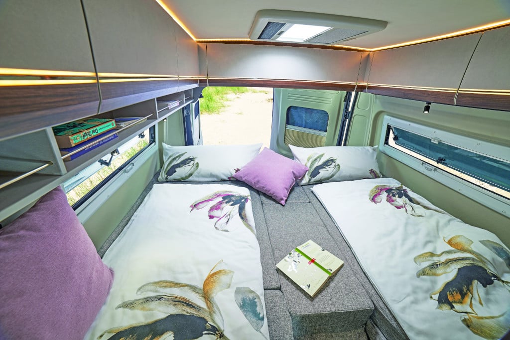 Zwei Einzel-Längsbetten mit Mittelauflage dazwischen vor halb geöffneter Hecktüre