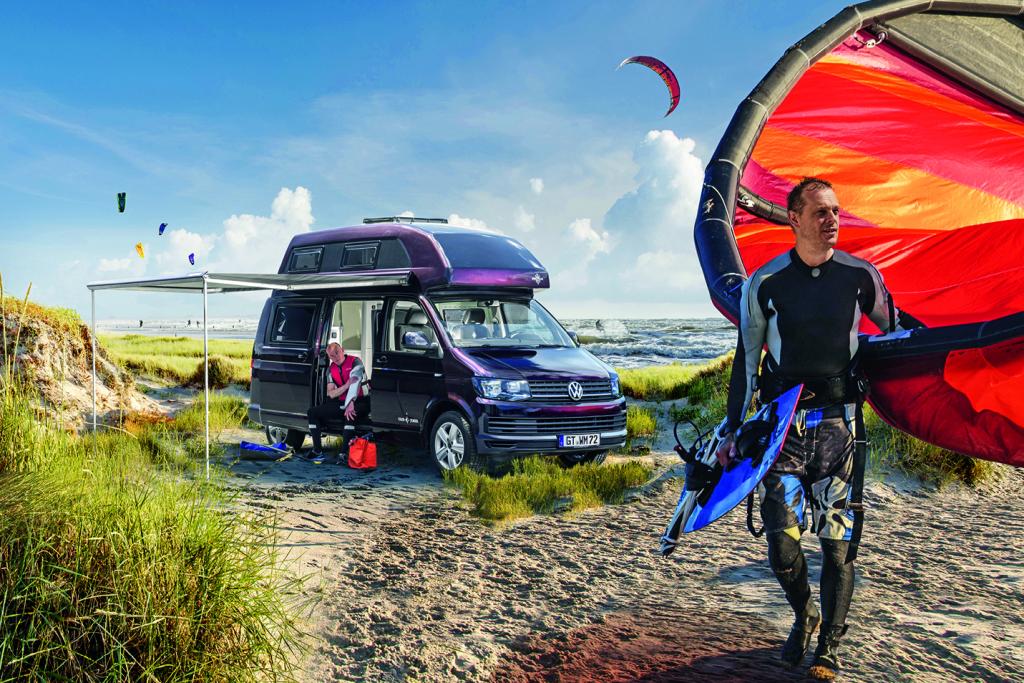 Aubergine-farbener Campingbus in den Dünen am Meer