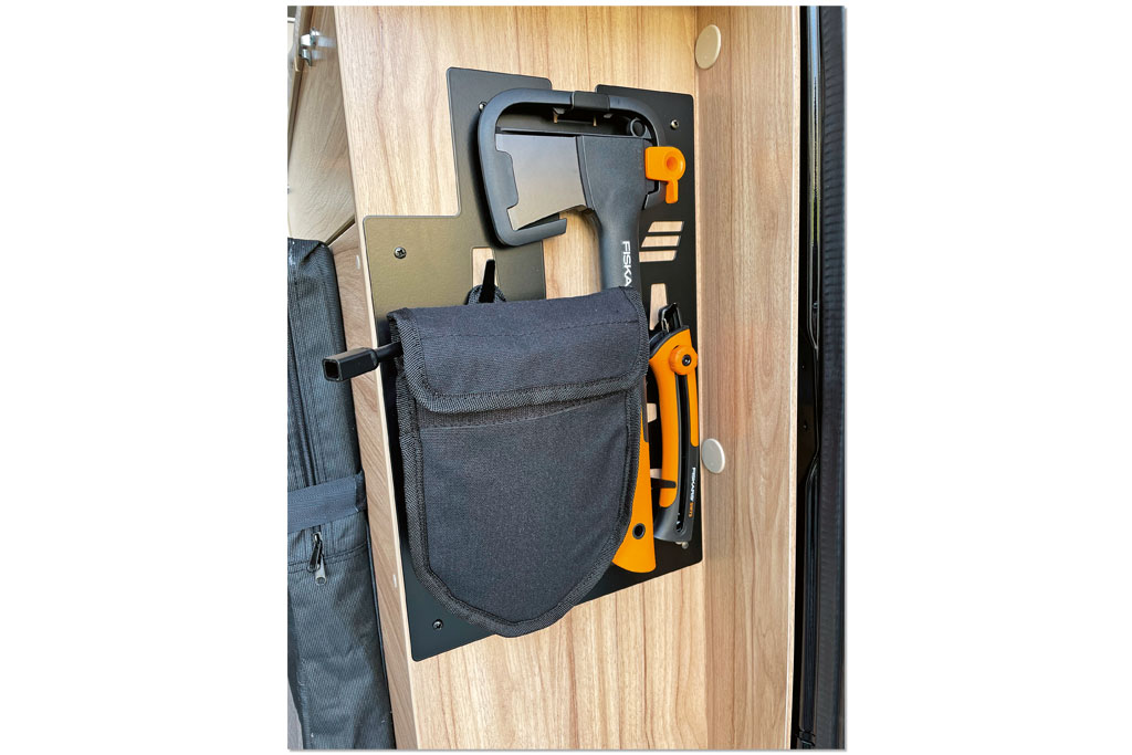 Tasche mit einer Axt befestigt an der Wand eines Möbelstücks im Campervan