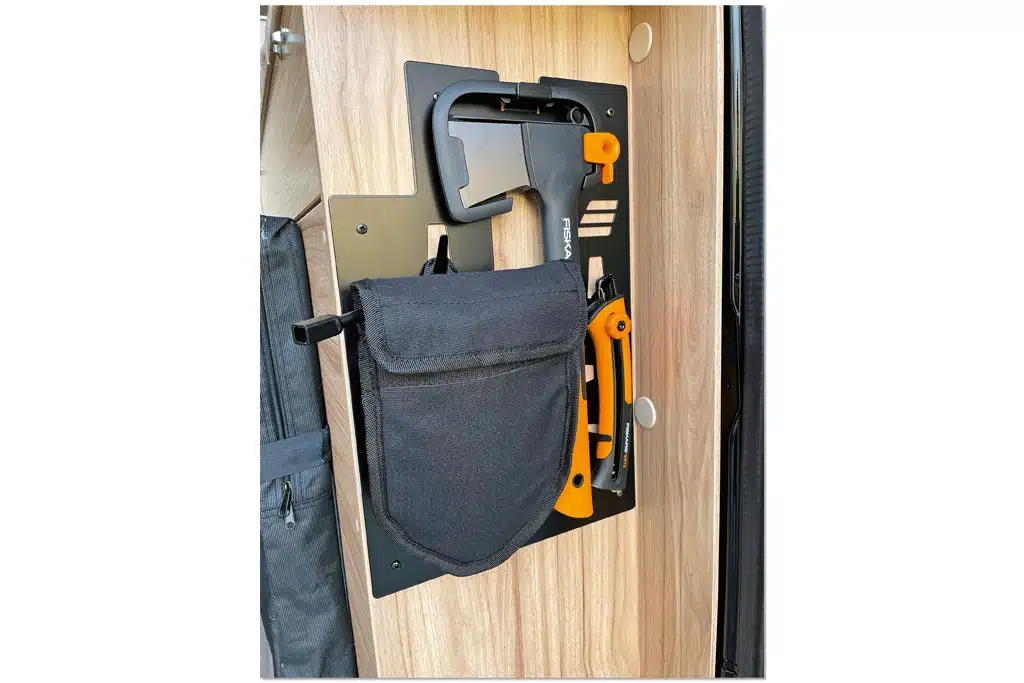Tasche mit einer Axt befestigt an der Wand eines Möbelstücks im Campervan