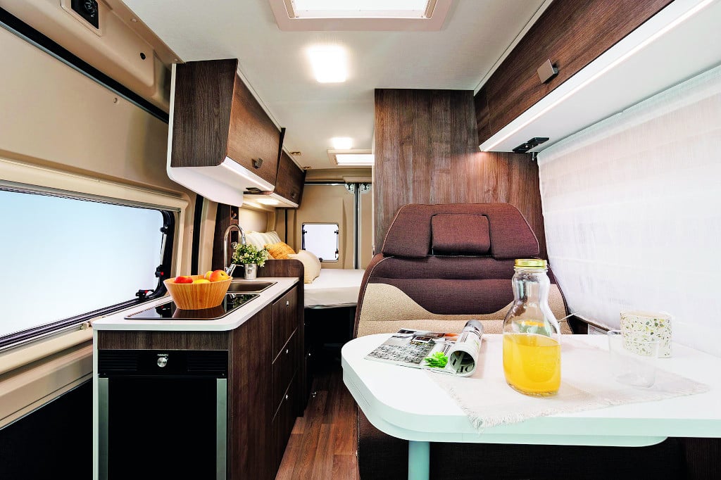 Innenansicht nach hinten, Sitzgruppe mit hellem Tisch und dunkelbraunem Polster und Möbeldekor.