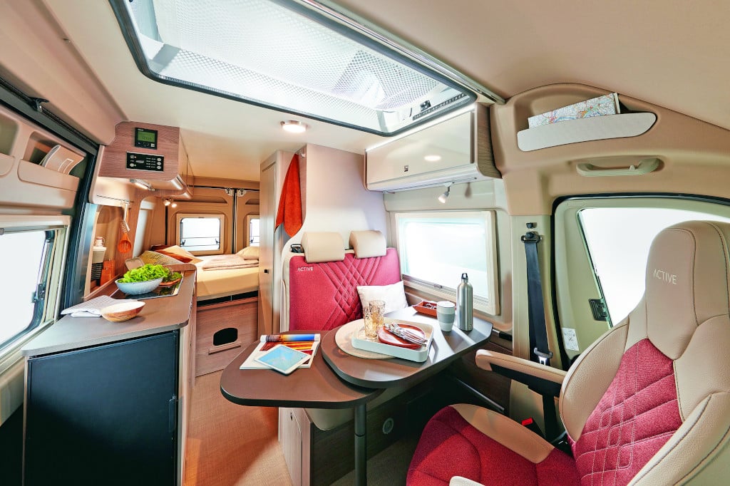 Innenansicht auf Sitzgruppe mit gedrehten Frontsitzen und roten Polstern, hellbraunes Holzdekor