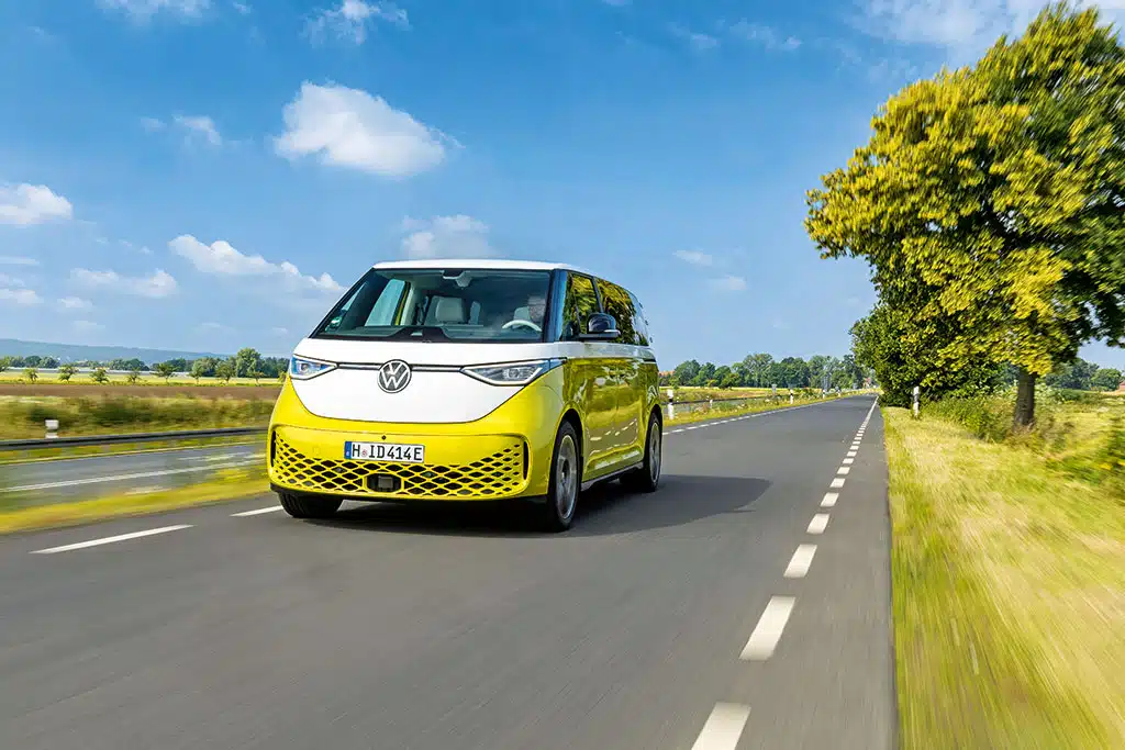 Gelb-weißer VW ID. Buzz auf einer Landstraße