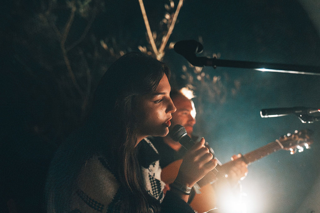 Eine Frau mit Mikrofon und ein Mann mit Gitarre bei einem Live-Musikauftritt outdoor am Abend