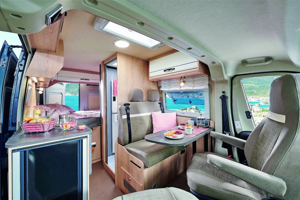 Sitzgruppe mit gedrehten Fahrersitzen, 2er-Sitzbank vor Duschkabine. Gegenüber Küchenblock, hinten Querbett.