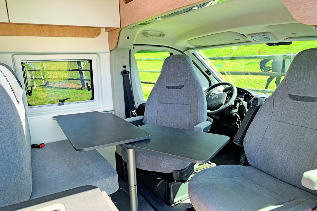 Blick von Schiebetüre nach schräg vorne, Fahrersitz gedreht, Tisch ausgeklappt