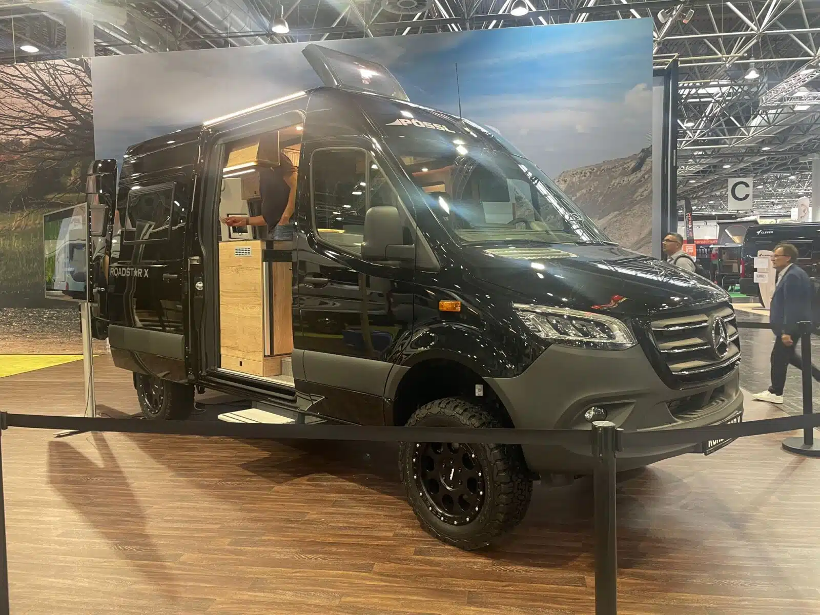 Schwarzer Campervan in einer Messehalle