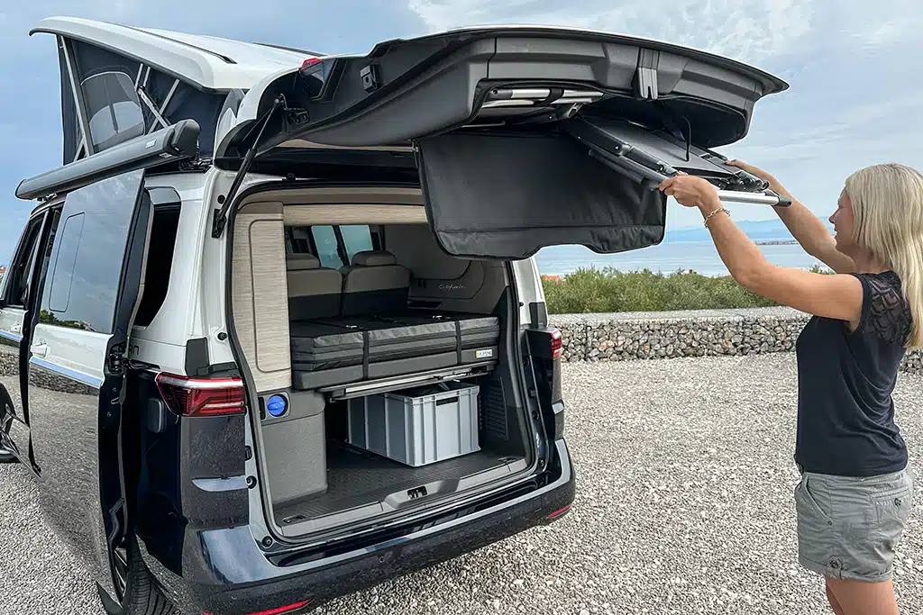 Frau nimmt Campingstühle aus einem Campervan.