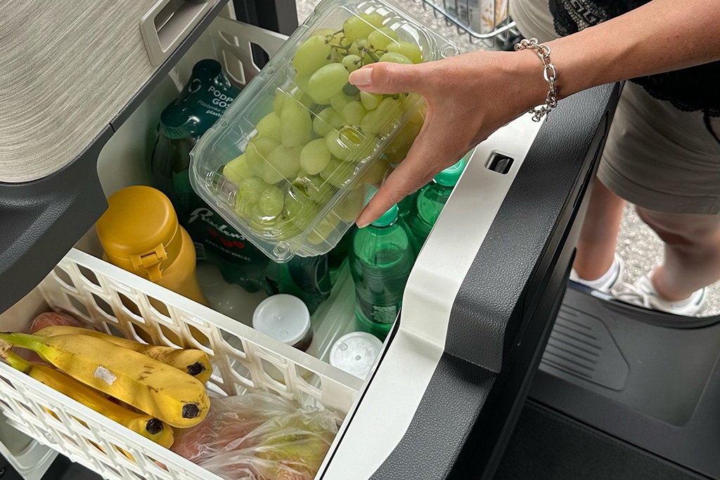 Obst wird in den Camping-Kühlschrank im VW California gelegt.