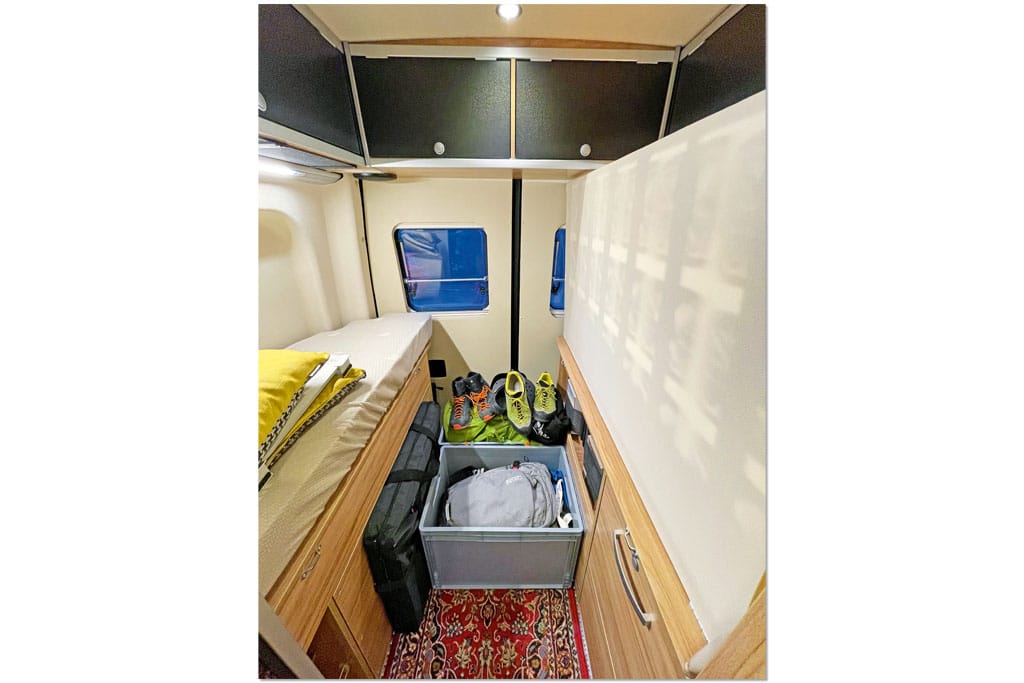 Mehrere graue Euroboxen mit Equipment im Mittelgang eines Campervans