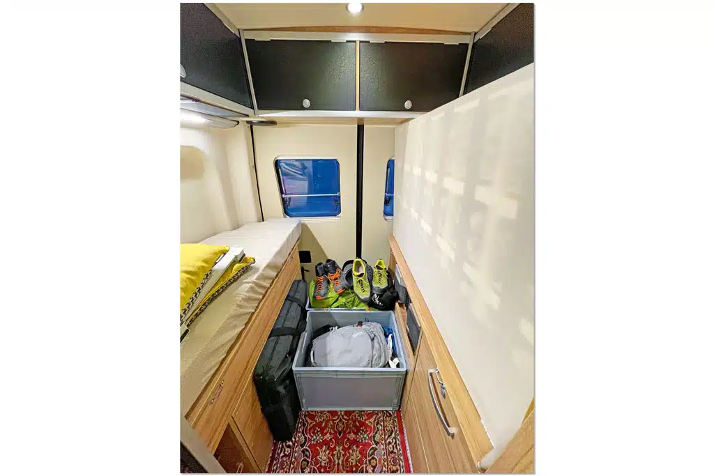 Mehrere graue Euroboxen mit Equipment im Mittelgang eines Campervans