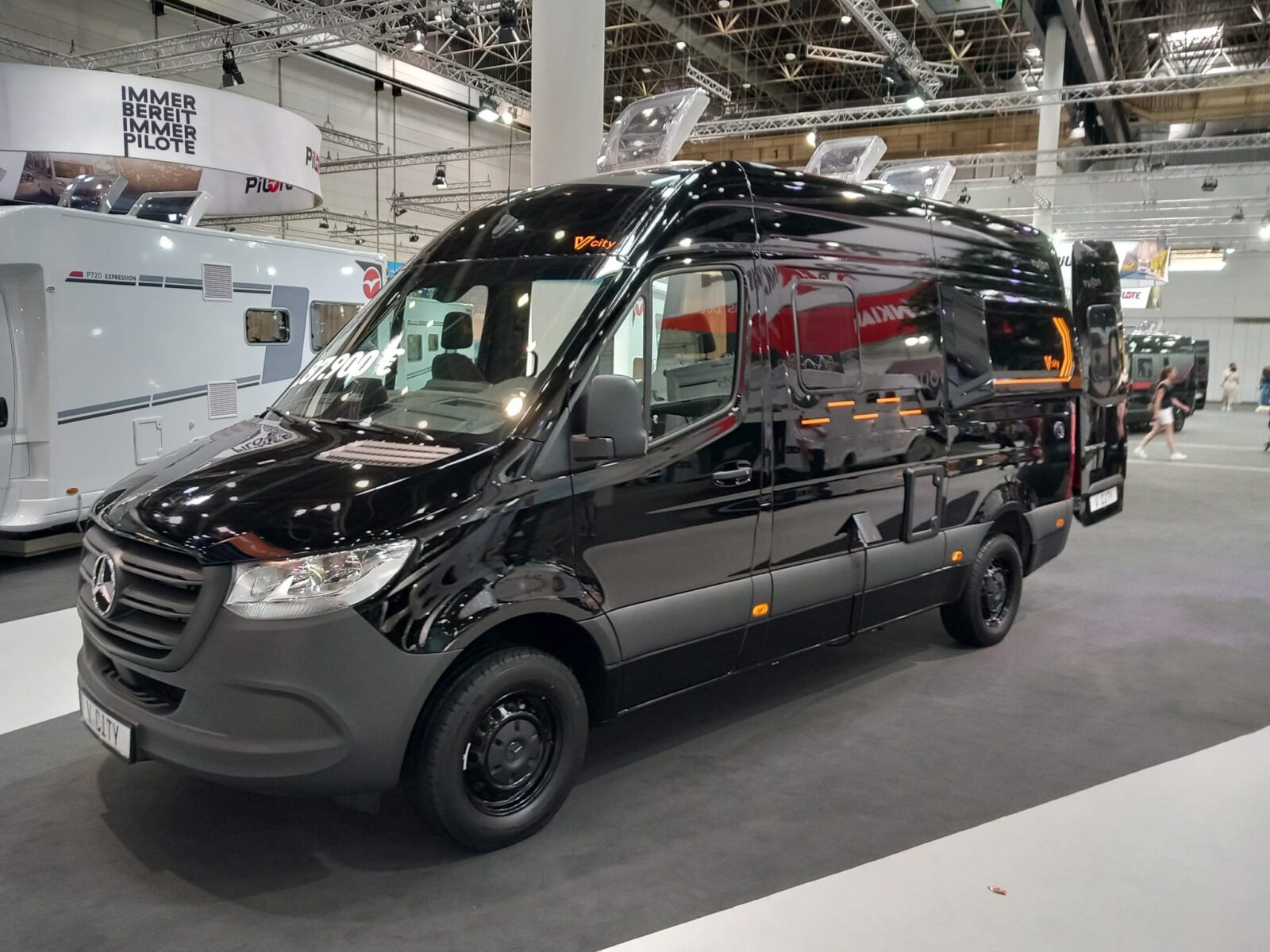 Schwarzer Campervan in einer Messehalle