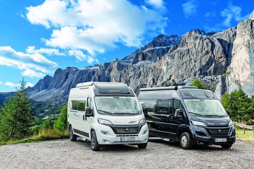 Weißer und schwarzer Campervan frontal-seitlich fotografiert vor bergiger Landschaft