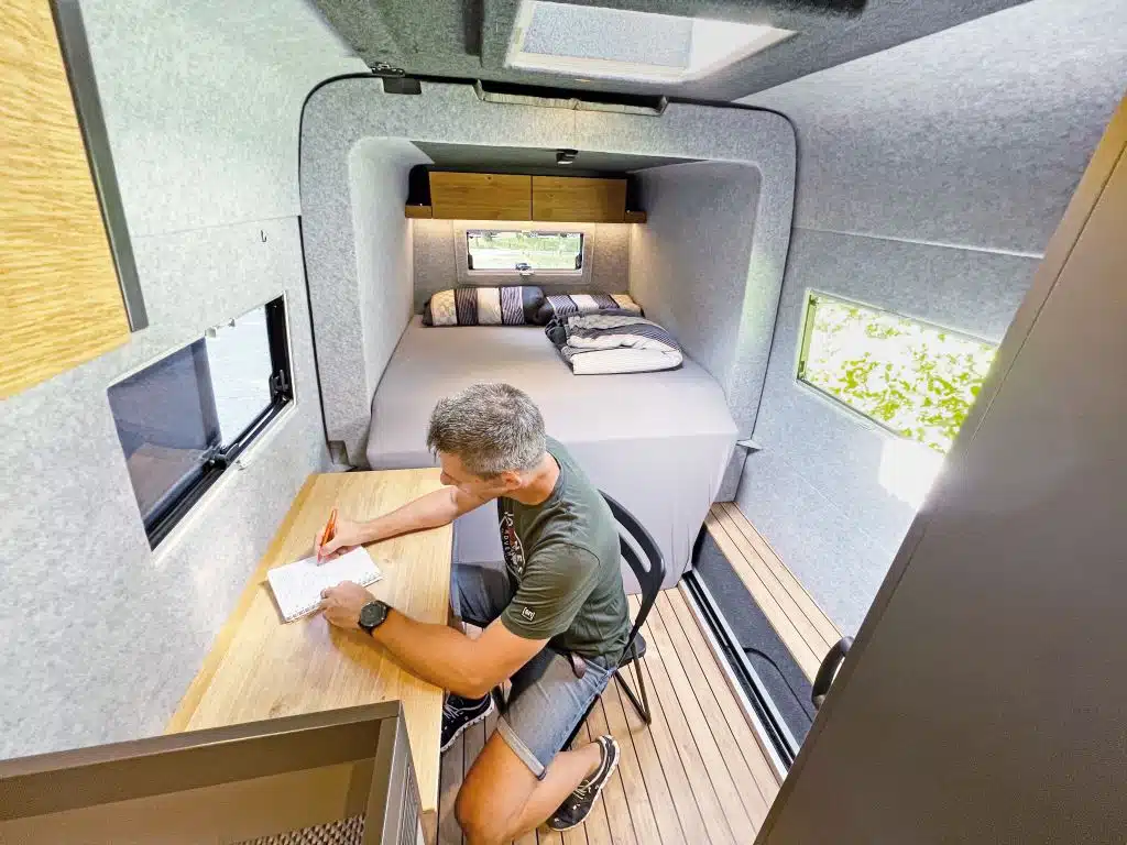 Wohnraum im Campervan, ein Mann sitzt an einem Tisch