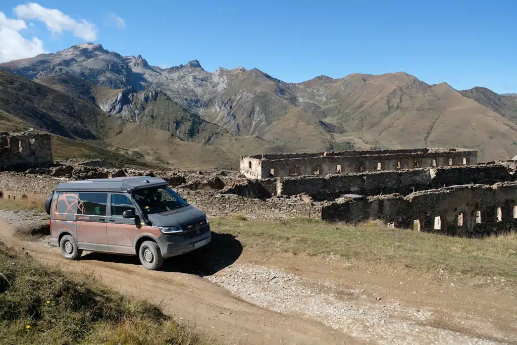 Ein Fahrzeug passiert eine alte Fort-Anlage, dahinter hohe Berge