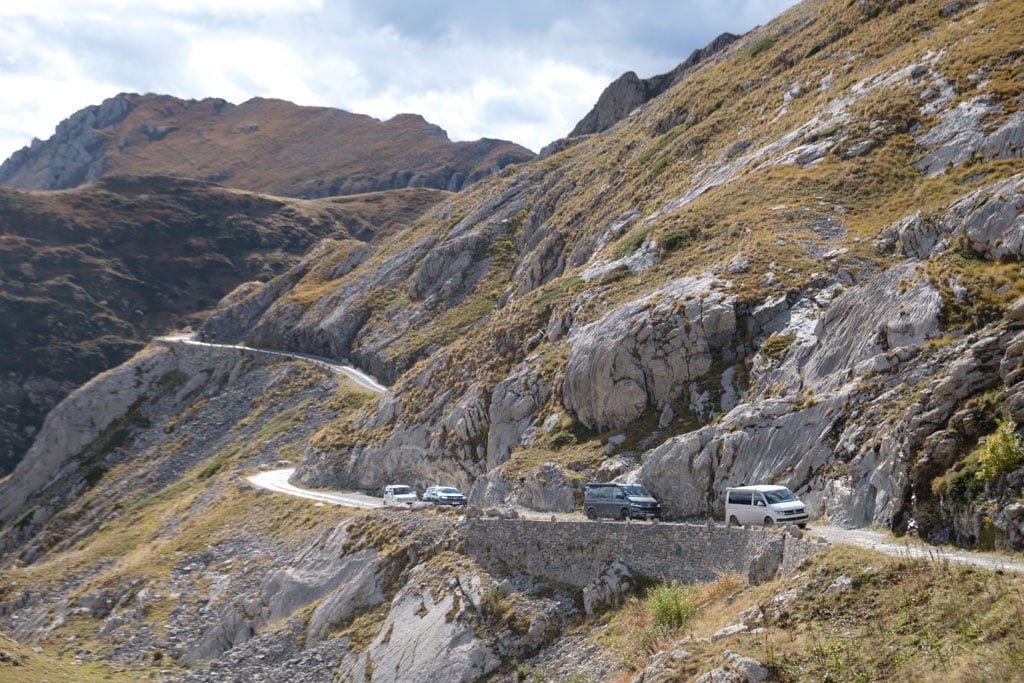 Vier Fahrzeuge fahren hintereinander auf einer Bergstraße