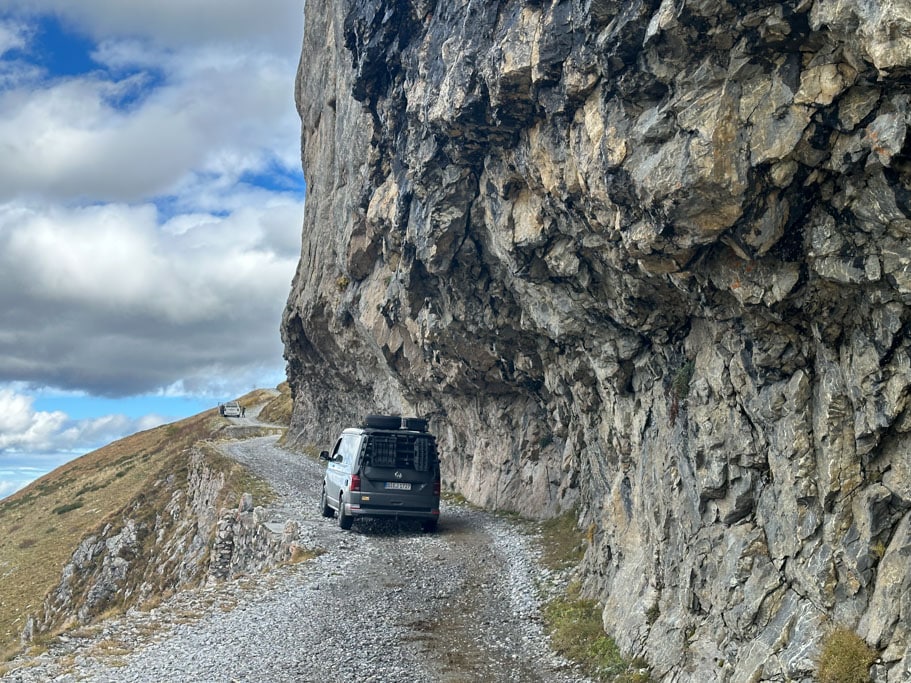 Ein Fahrzeug auf einer Bergstraße, links davon der Berghang, rechts davon steile Felswände