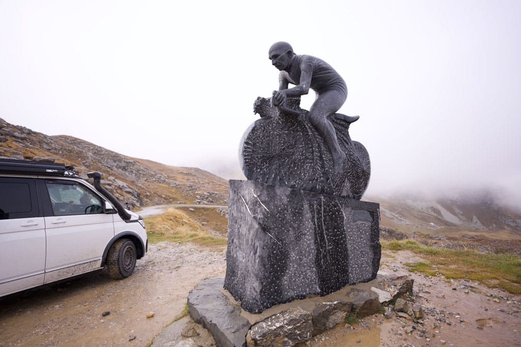 Eine Stein-Statue eines Mountainbikers auf einer Berganhöhe