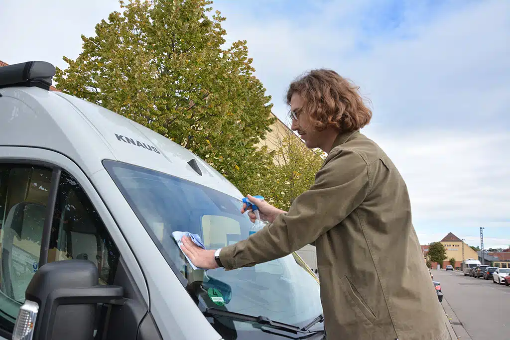 Steinschlag reparieren: Mann putzt Scheibe von Wohnmobil