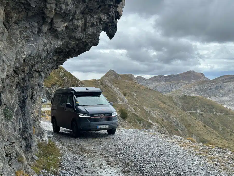 Dunkelgrauer VW Bus auf steiniger Straße im Gebirge