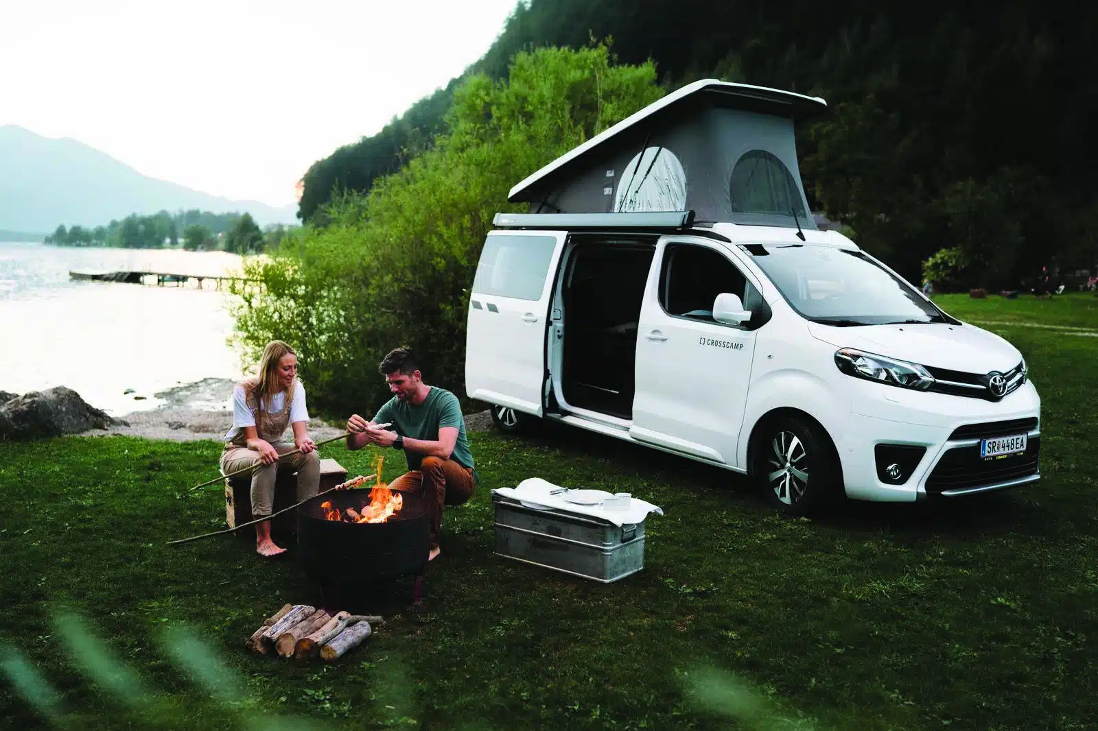 Foto Oberösterreich Tourismus GmbH/Moritz Ablinger: Ein Paar grillt über einer Feuerstelle am Campingplatz Berau St. Wolfgang im Salzkammergut.