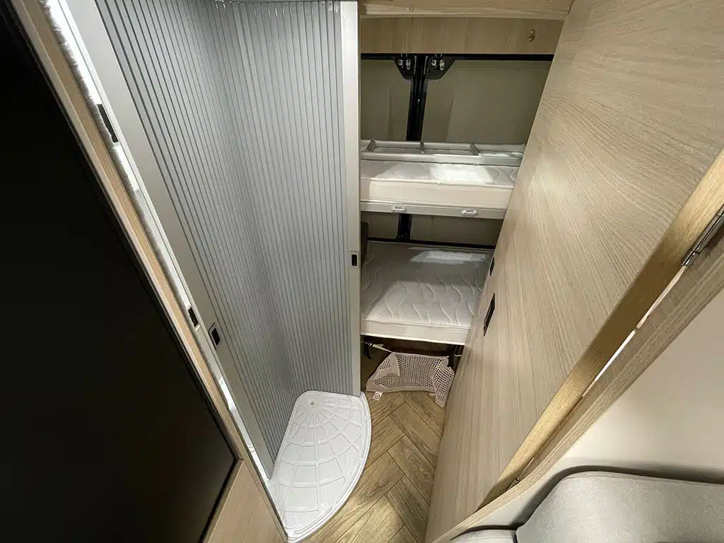 Wohnbereich im Campervan mit Stockbetten und kleiner Dusche