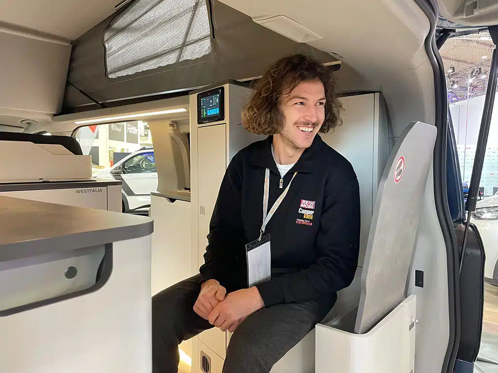 Mann sitzt auf Toilettensitz in einem Campingbus