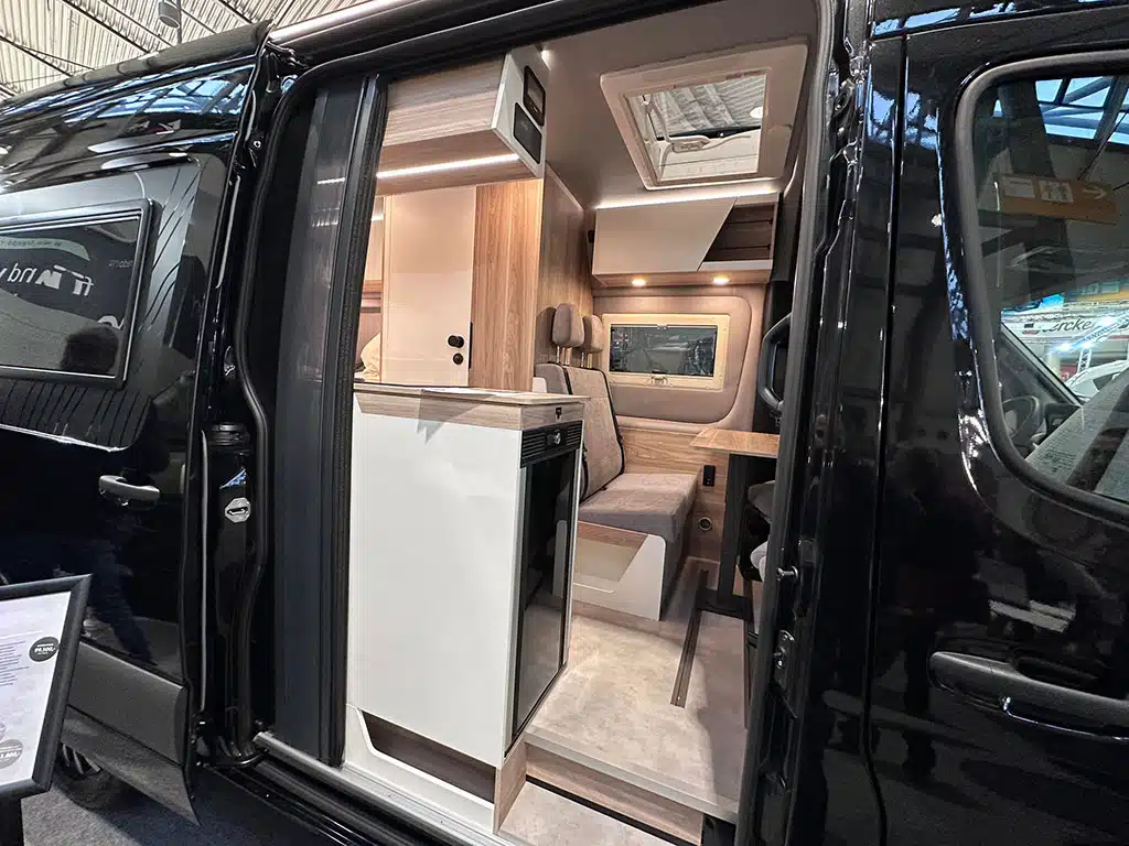 Blick auf Wohnausbau eines schwarzen Campervans durch geöffnete Schiebetür