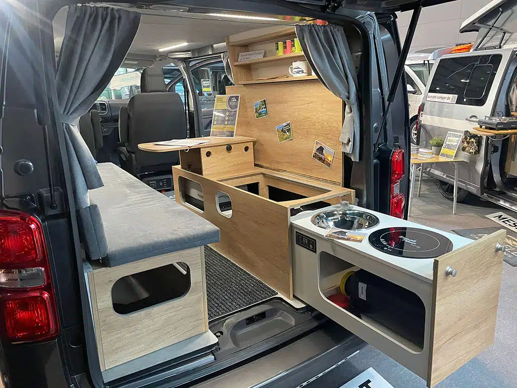 Blick durch die offene Heckklappe auf auf den Campingausbau eines Campervans mit am Heck ausziehbarer Küche