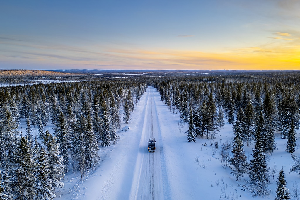Campervan fährt durch verschneiten Wald in Skandinavien.