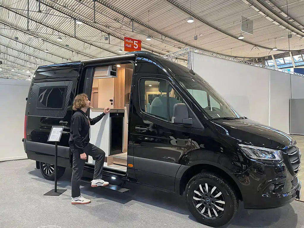 Schwarzer Kastenwagen mit Campingausbau in Messehalle