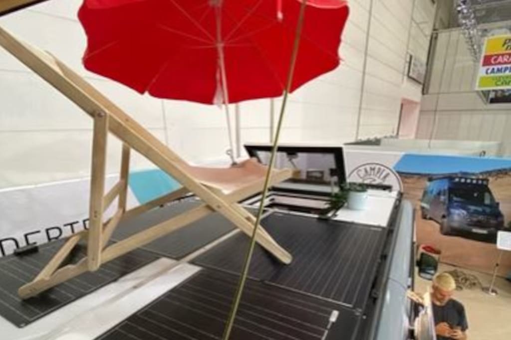 Dachterrasse des Campers mit Klappstuhl auf begehbaren Solarmodulen. Im Hintergrund ist Dachluke geöffnet.