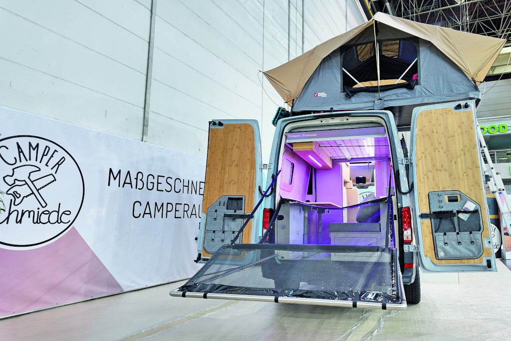 Camper von hinten, aufgestelltes Dachzelt und Hängemattenkonstruktion an geöffneten Hecktüren