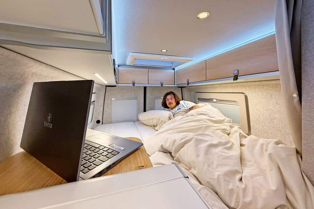 Man liegt im Bett und schaut etwas am Laptop an im Hymer Grand Canyon S 700.