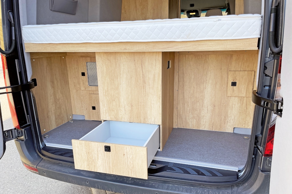 Im Stauraum unter dem Bett hinten ein mittig befestigter zusätzlicher Schrank mit Schublade unten