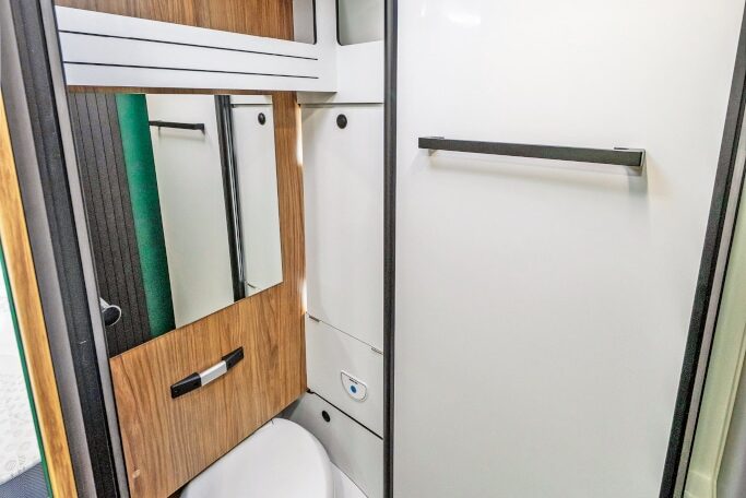 Karmann Dusche mit versenkter Toilette und nach rechts vor das Fenster geklapptes Waschbecken