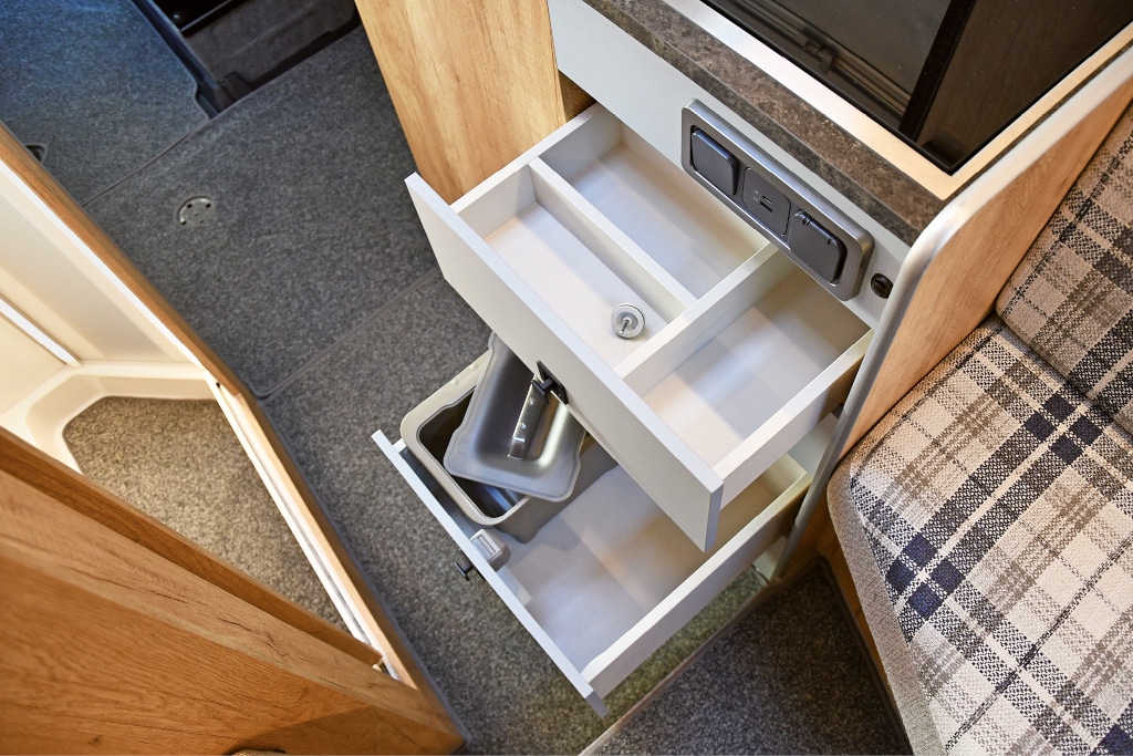 Blick von schräg oben auf geöffnete Schubladen, die oberste mit Besteckeinsatz