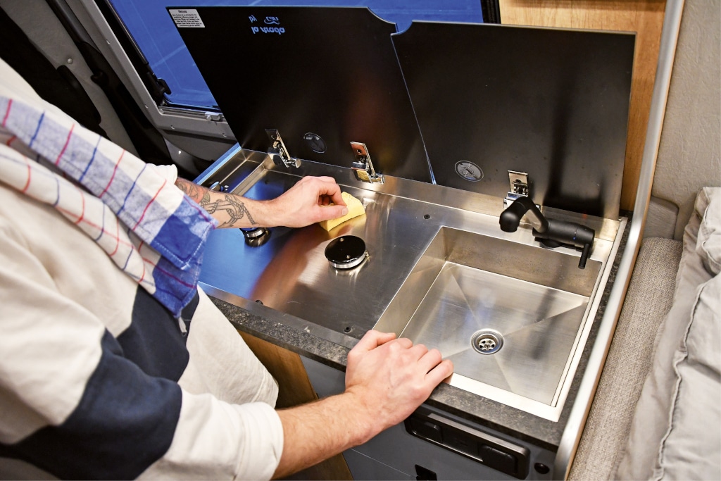 Blick auf 2-Flamm-Herd und Spüle mit hochgeklappter Abdeckung.