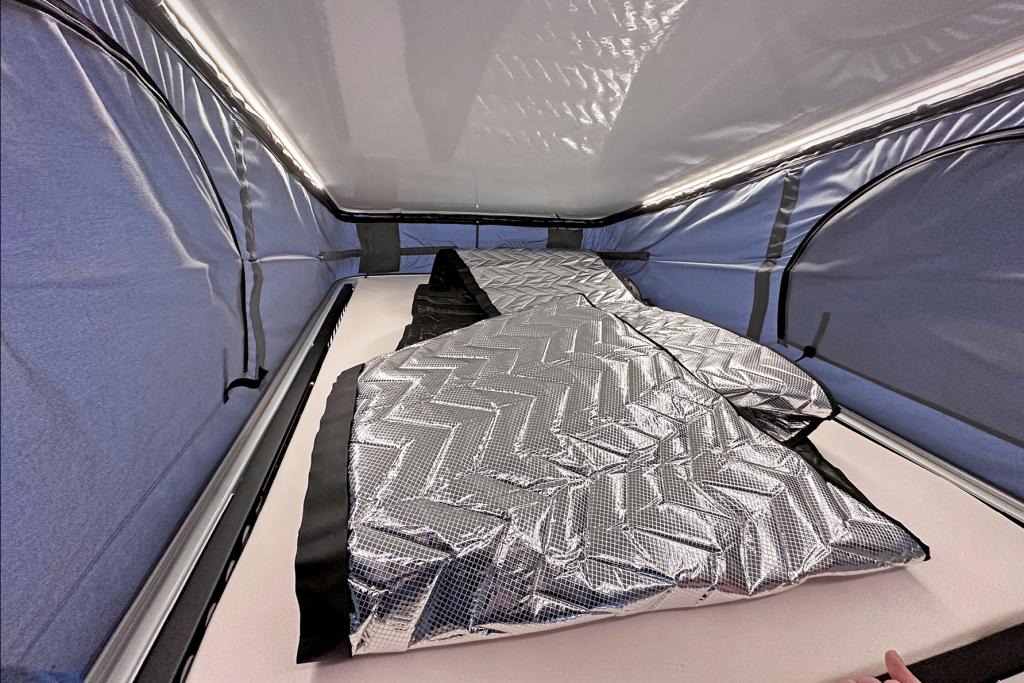 Isoliermatten liegen auf einer Matratze in einem Aufstelldach.