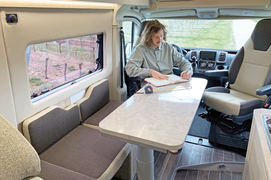 Mann sitzt an ausgezogenem Tisch im Essberecih auf gedrehtem Fahrersitz