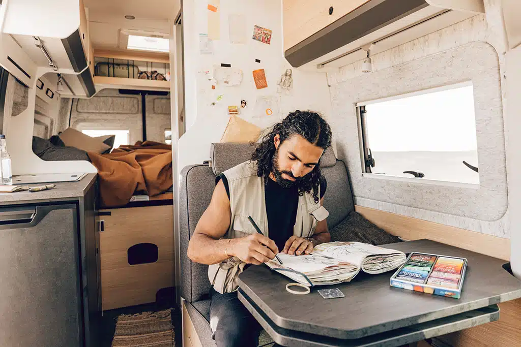 Hipster zeichnet Selbstportrait in Campervan-Studie