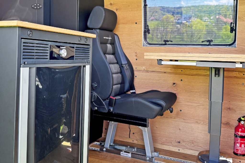 Einzelsitz auf Befestigungs-Schienen am Essplatz. Im Vordergrund der Kühlschrank stirnseitig am Küchenblock.