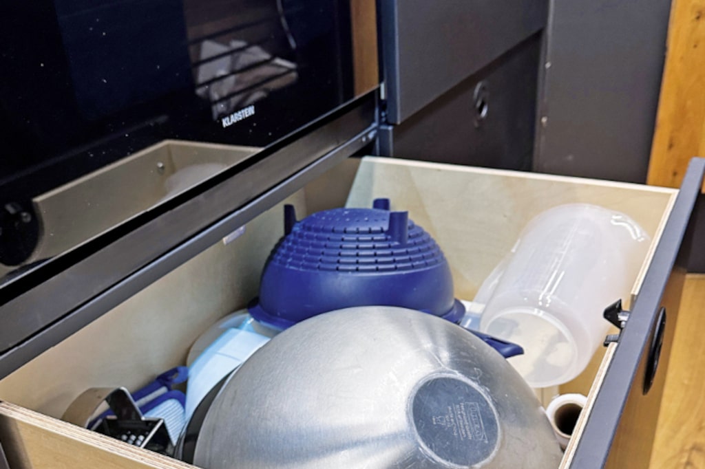 Offene Schublade unter dem Backofen mit Sieb und Schüsseln