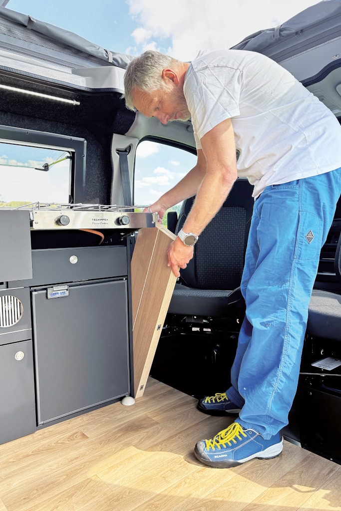 Mann verstaut die Tischplatte zwischen Küchenblock und Fahrersitz