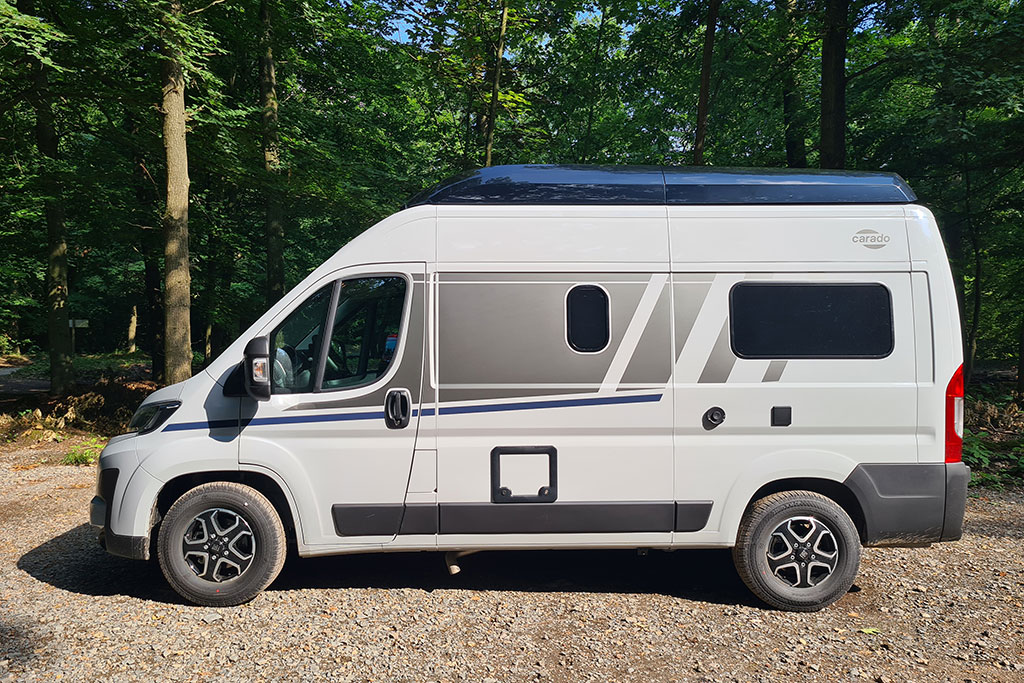 Seitenansicht eines weißen Campervans auf Waldparkplatz