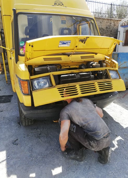 Mann repariert etwas am Fahrzeug