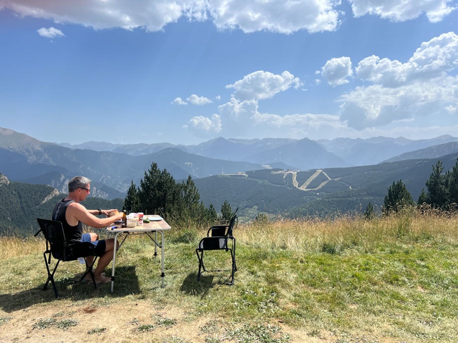 Frau auf Campingstuhl am Campingtisch in den Bergen