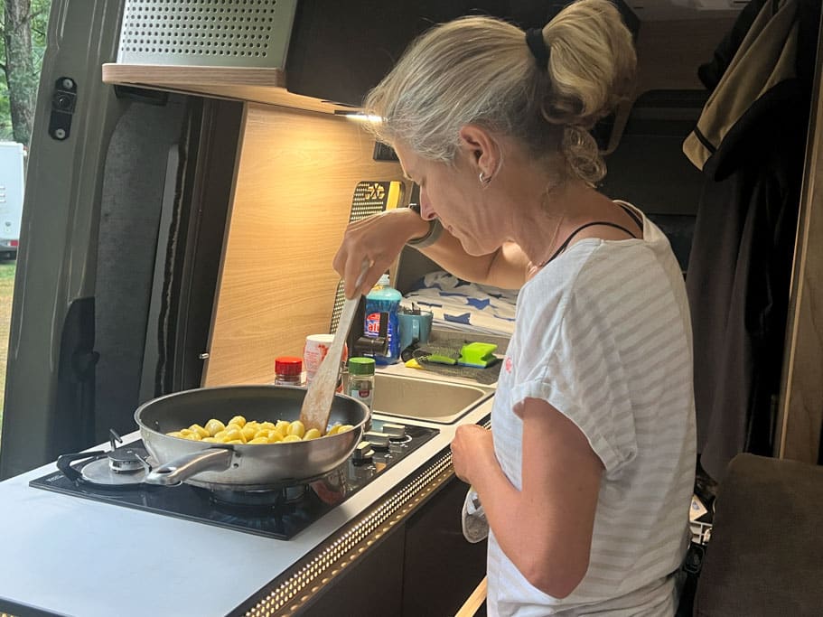 Frau kocht im Campervan