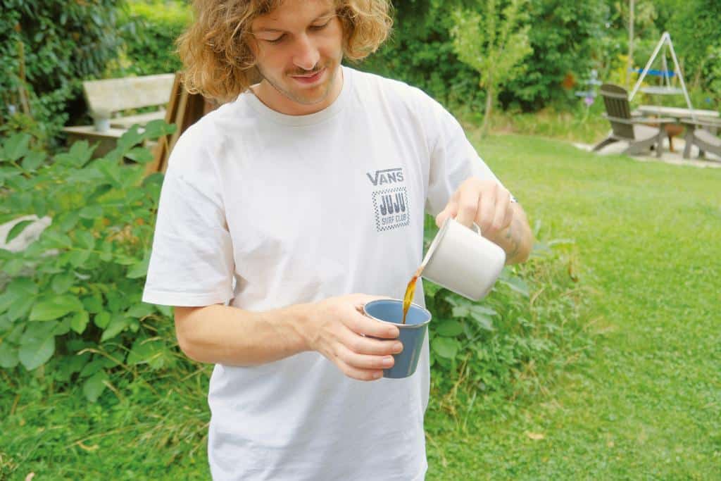 Mann kippt Kaffee in einen Becher