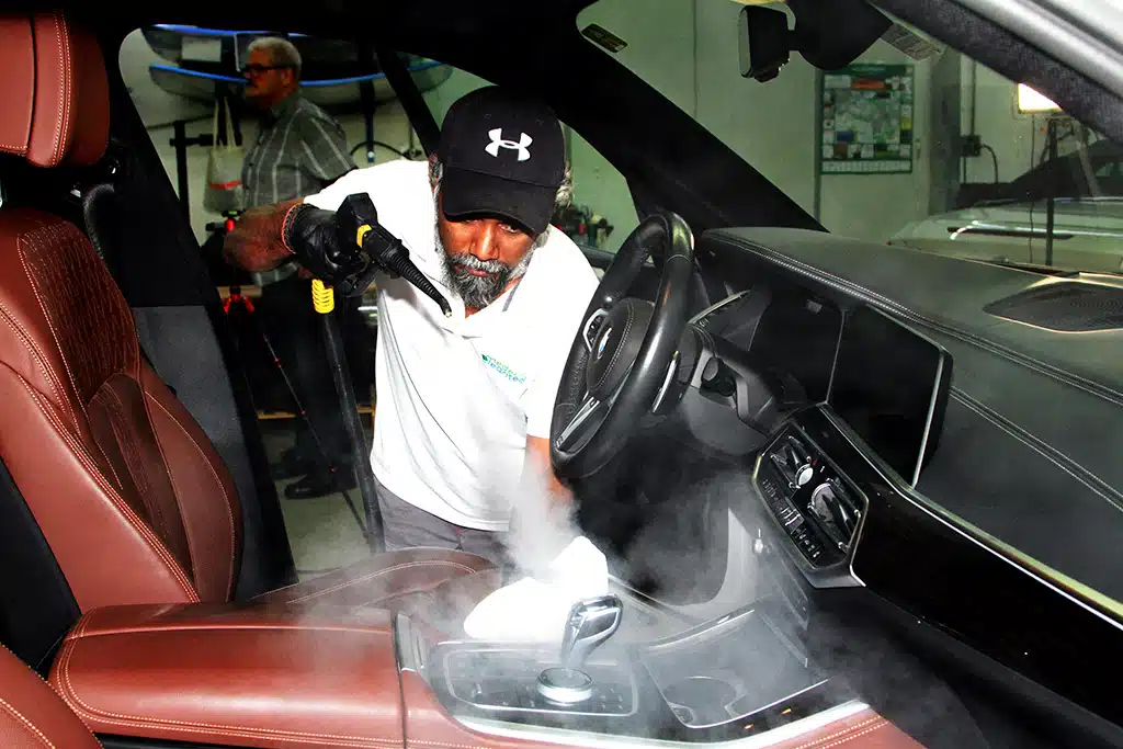 Ein Mann reinigt das Fahrerhaus eines Fahrzeugs mit dem Mikrotrockendampfreiniger Micro Cleaner von Medeco Cleantec, zu sehen ist der weiße Wasserdampf.